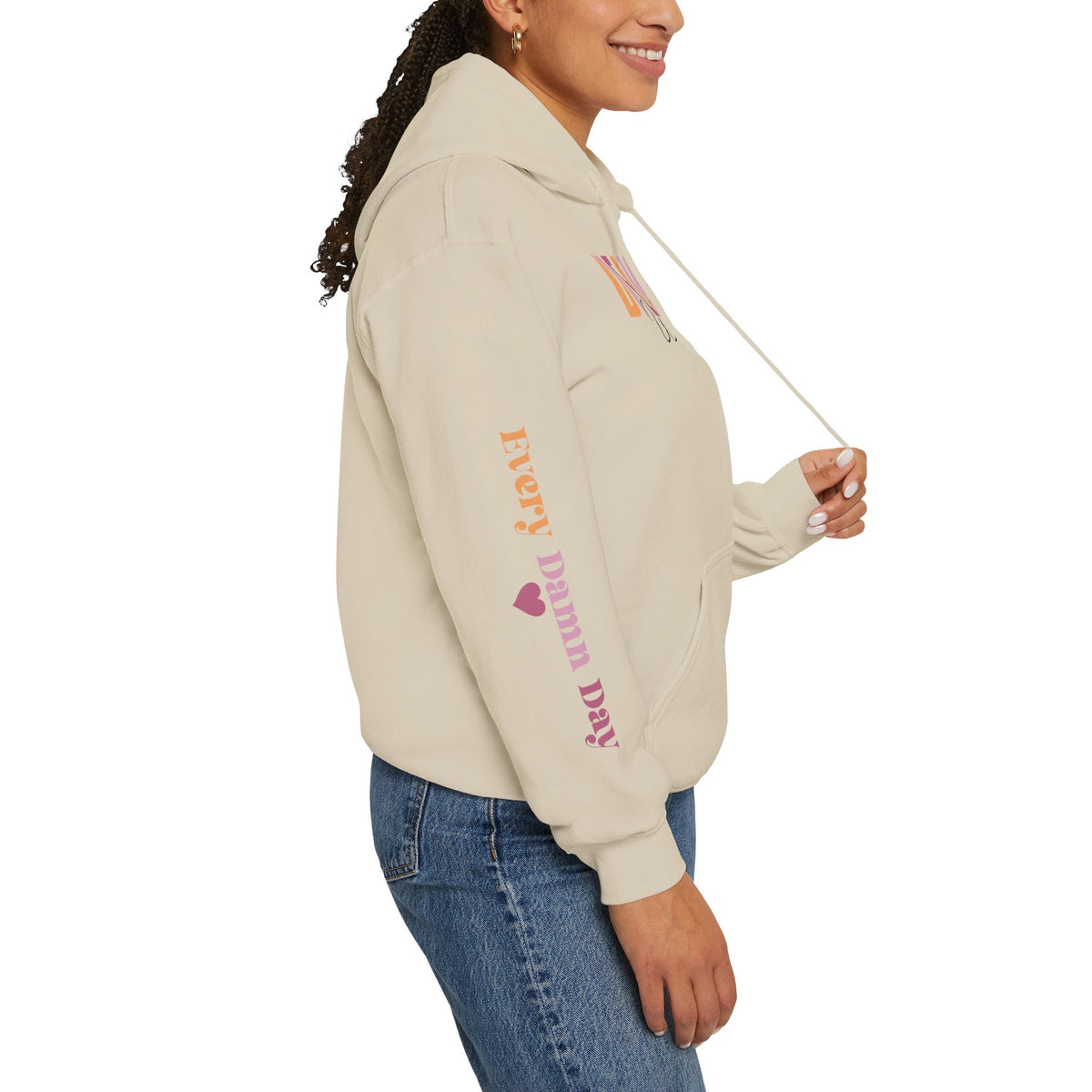 Person wearing a beige hoodie with a sleeve 'EVERY DAMN DAY' with a heart, paired with blue jeans, shown from a side profile against a white background.