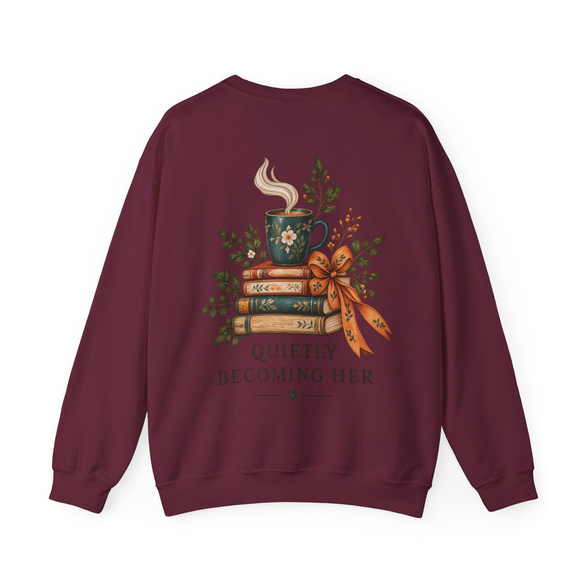 A maroon crewneck sweatshirt shown from the back, featuring a graphic of a steaming green mug on stacked books tied with a ribbon, surrounded by greenery, with the text 'QUIETLY BECOMING HER'.