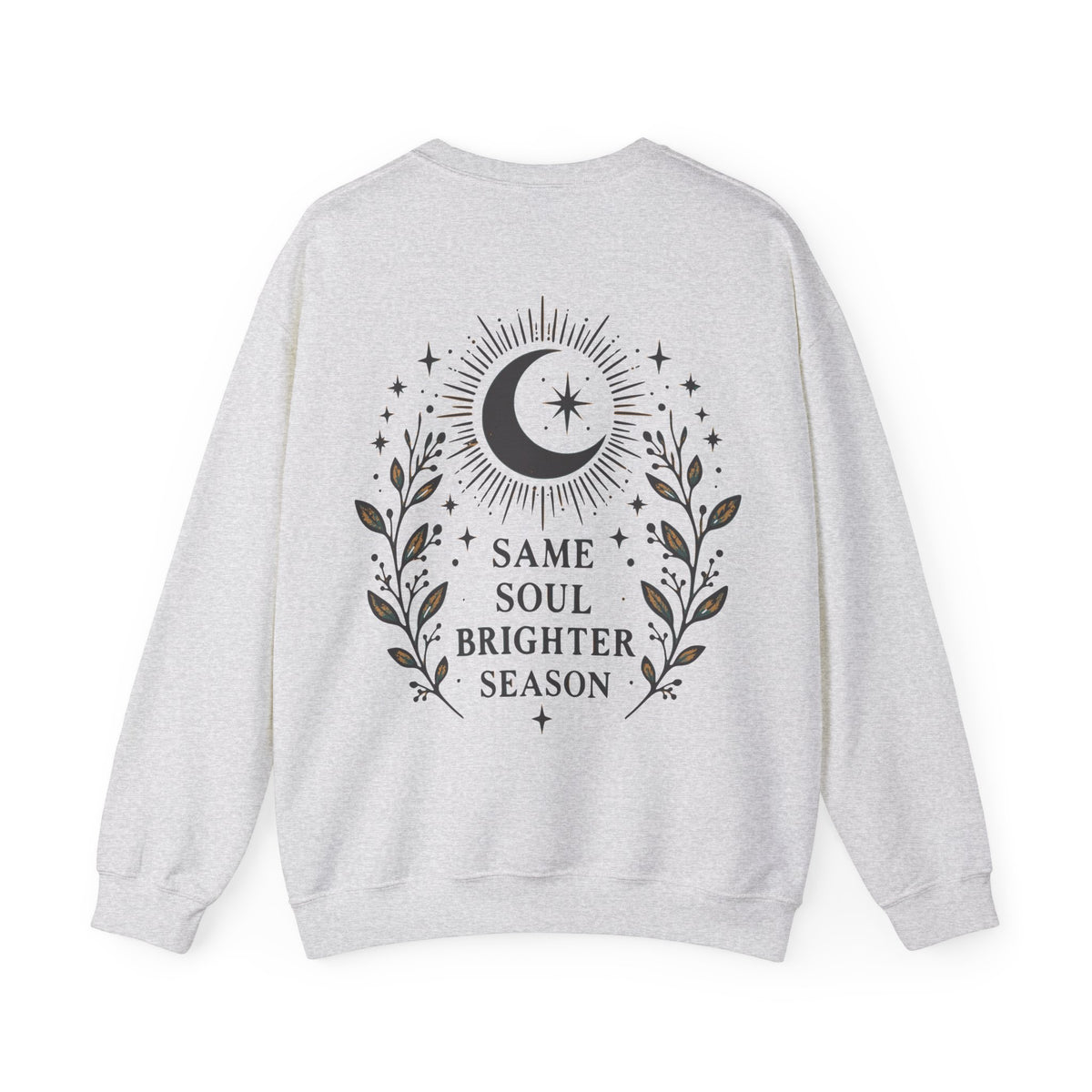 A light heather gray crewneck sweatshirt shown from the back, featuring a black graphic of a crescent moon, stars, and leafy branches with the text 'SAME SOUL BRIGHTER SEASON'.