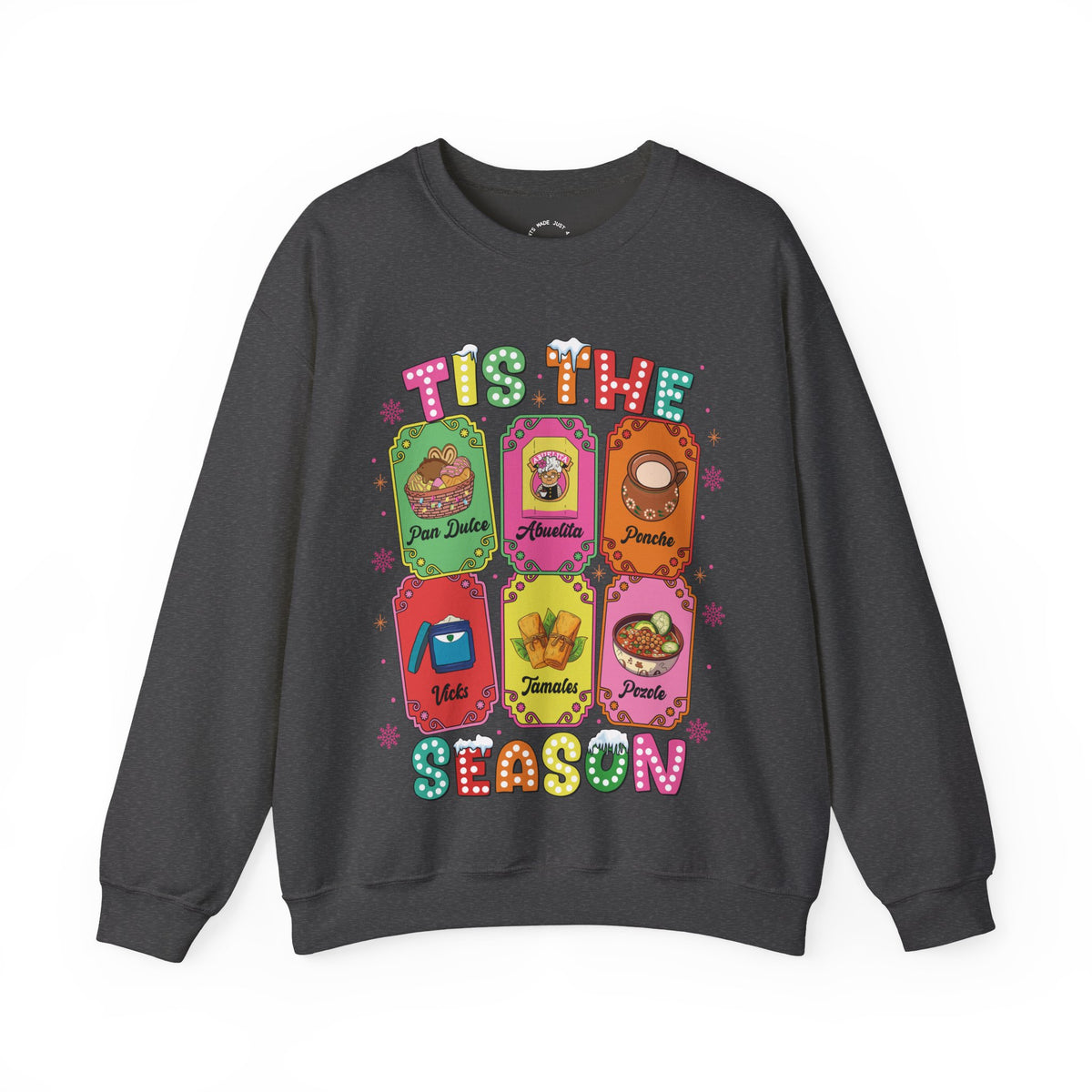 An olive green crewneck sweatshirt featuring a colorful graphic print of six Christmas-themed ticket illustrations with Latino traditions with the text 'TIS THE SEASON' in a retro, bubbly font.