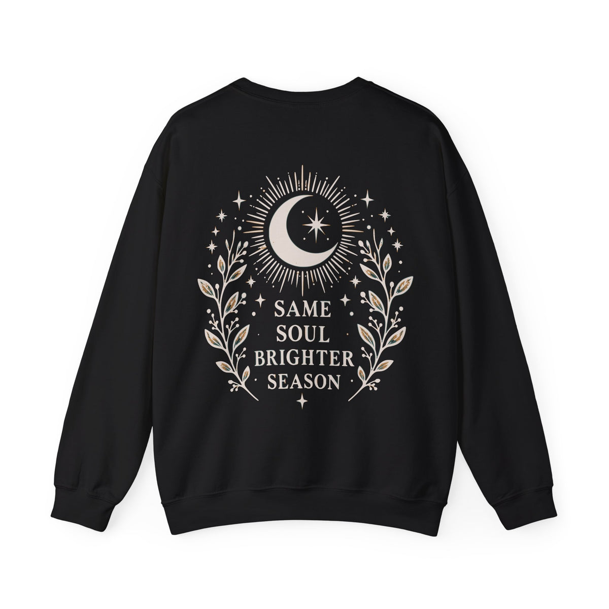 A black crewneck sweatshirt shown from the back, featuring a cream graphic of a crescent moon, stars, and leafy branches with the text 'SAME SOUL BRIGHTER SEASON'.