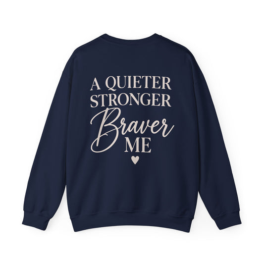 A navy blue crewneck sweatshirt shown from the back, featuring the text 'A QUIETER STRONGER Braver ME' in cream lettering with a small heart below, on a plain white background.
