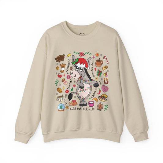 A beige crewneck sweatshirt featuring a colorful graphic of a cartoon donkey wearing a Santa hat, surrounded by festive Christmas illustrations and text, displayed on a clean white background.