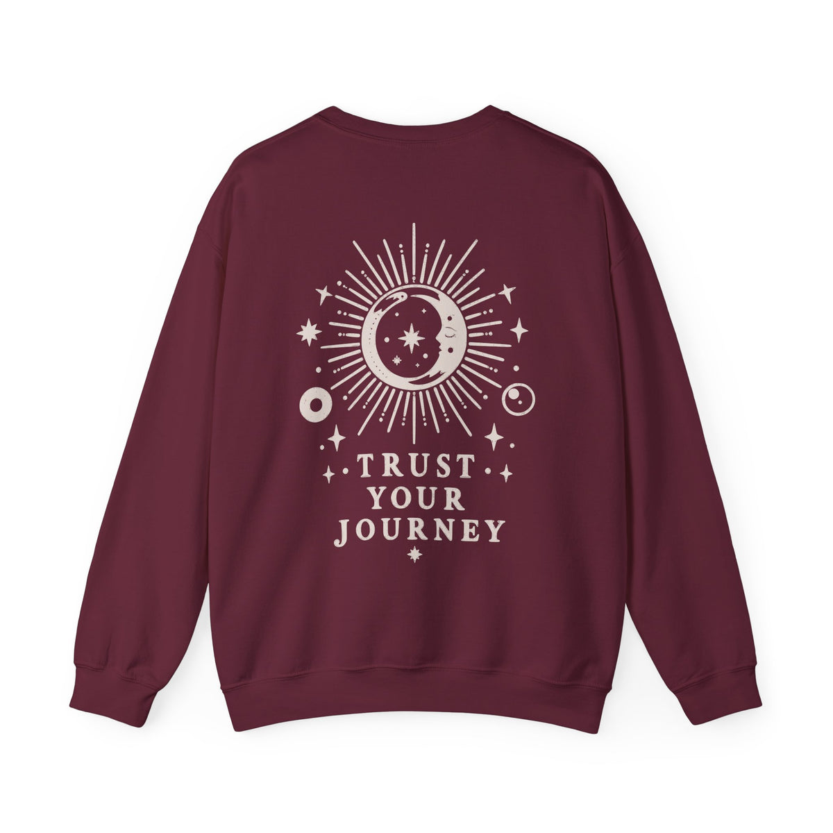 A maroon crewneck sweatshirt with a cream celestial graphic on the back featuring a sun, moon, stars, and the text 'TRUST YOUR JOURNEY'.
