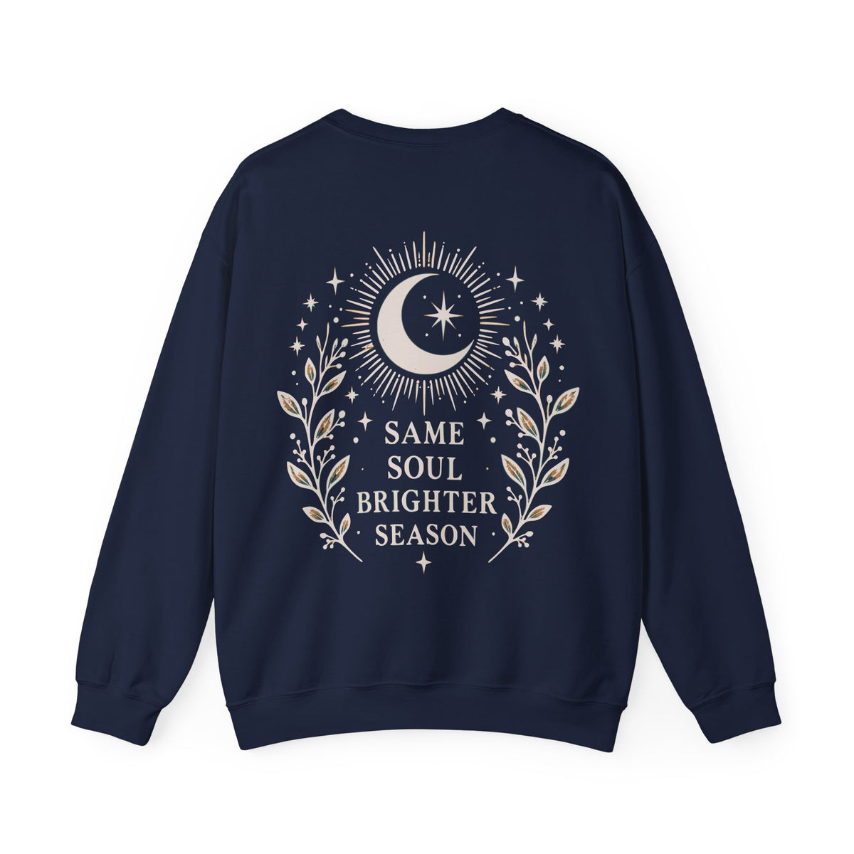 A navy blue crewneck sweatshirt shown from the back, featuring a cream graphic of a crescent moon, stars, and leafy branches with the text 'SAME SOUL BRIGHTER SEASON'.