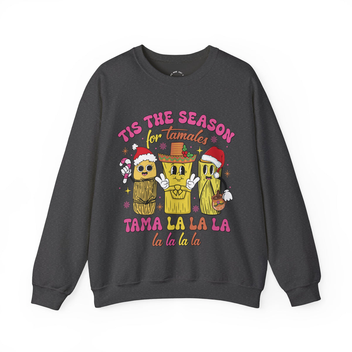 A dark gray crewneck sweatshirt featuring a colorful graphic of three tamale characters wearing Santa hats and a sombrero, with the text 'TIS THE SEASON for Tamales' and 'TAMA LA LA LA la la la la'.
