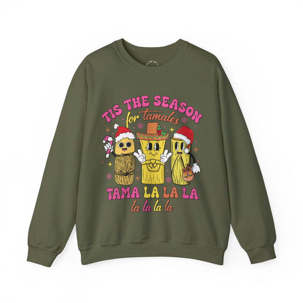 An olive green crewneck sweatshirt featuring a colorful graphic of three tamale characters wearing Santa hats and a sombrero, with the text 'TIS THE SEASON for Tamales' and 'TAMA LA LA LA la la la la'.