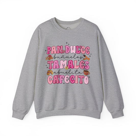 A heather gray crewneck sweatshirt featuring a colorful graphic print on the front with the Spanish text 'Pan Dulce Bunuelas Tamales Abuelita Cafecito' in pink and brown donut-style lettering with small illustrations of food items.