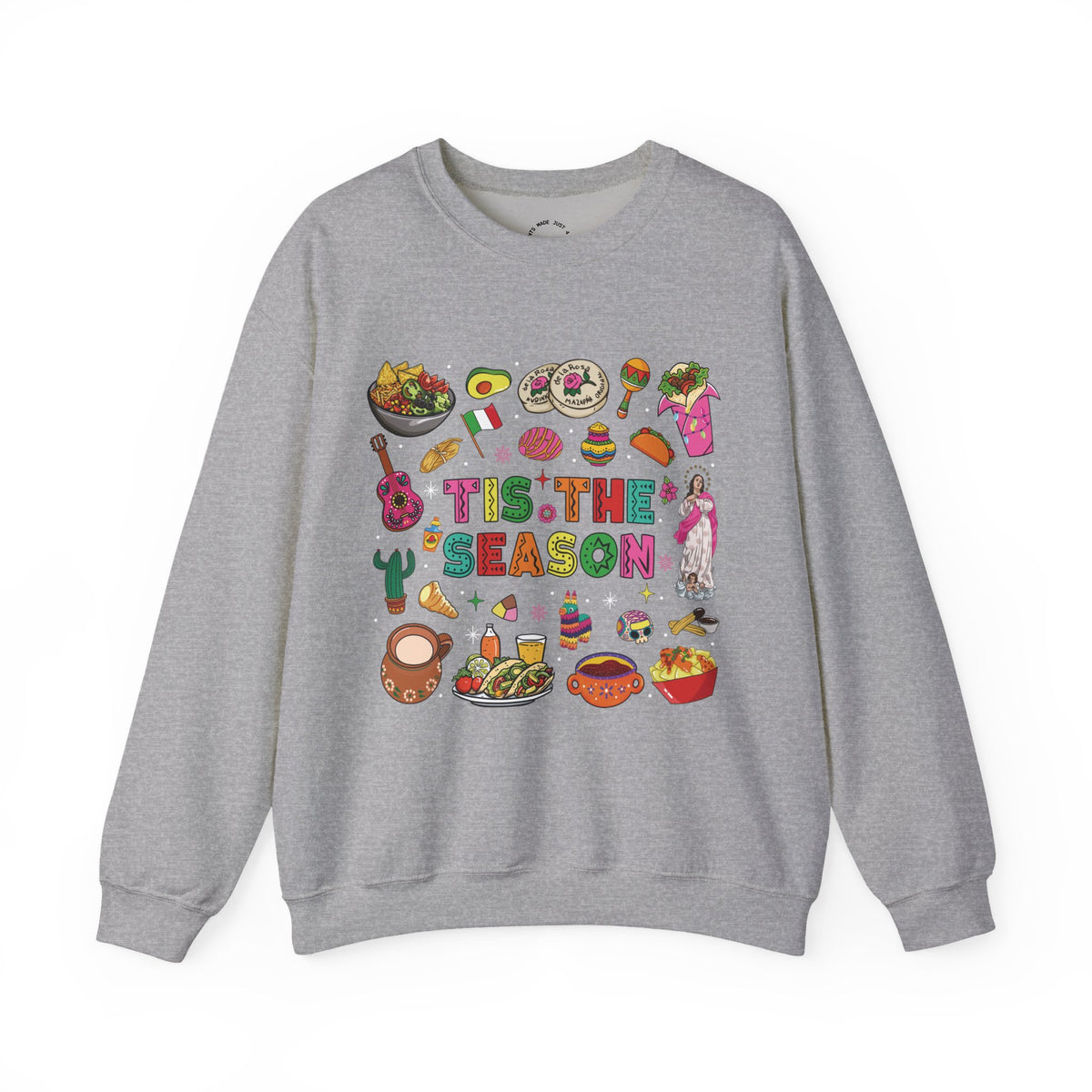 A heather gray crewneck sweatshirt featuring a colorful graphic print on the front with the text 'Tis the Season' surrounded by various cozy mexican illustrations like hot cocoa, burritos, tacos, pinata, and more seasonal traditions.