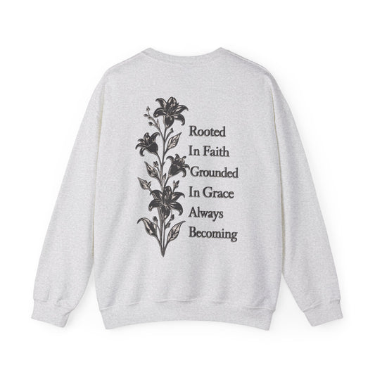 A light heather gray crewneck sweatshirt shown from the back, featuring a black graphic of a lily of the valley next to the text 'Rooted In Faith Grounded In Grace Always Becoming'.